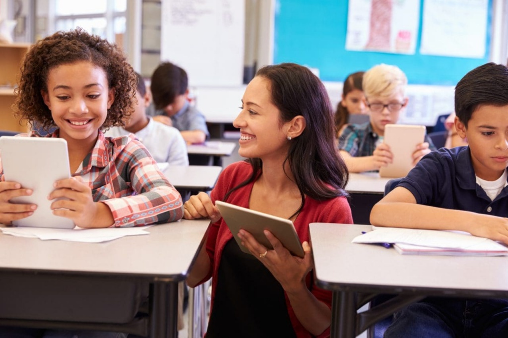 Teacher,among,kids,with,computers,in,elementary,school,class