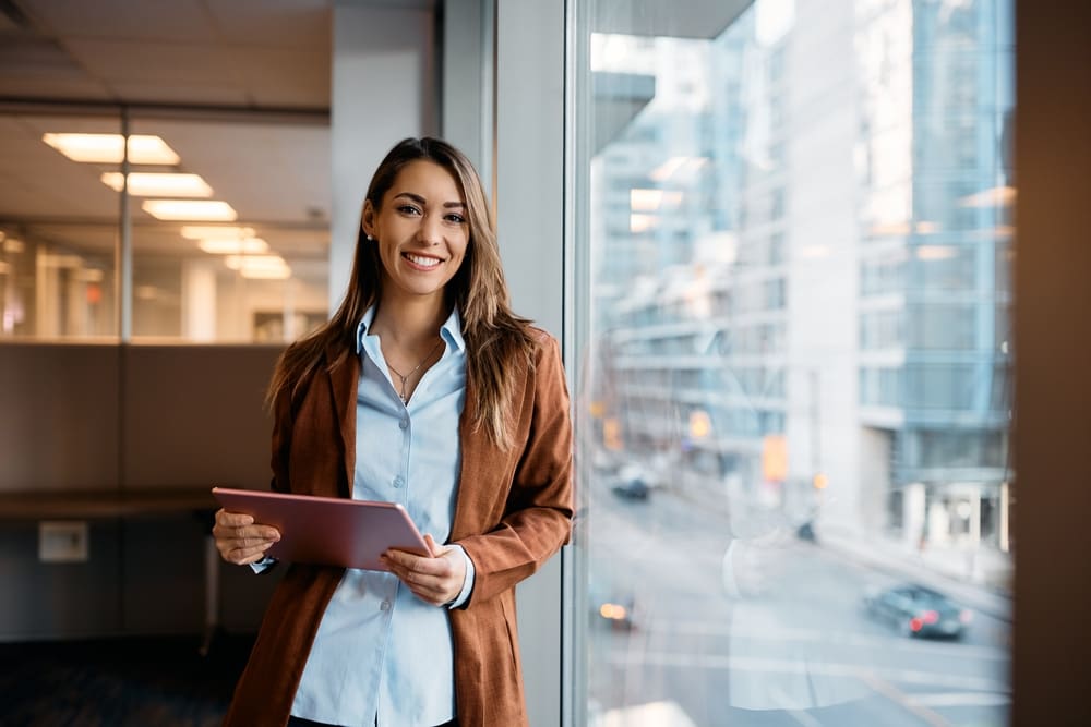 Young,happy,businesswoman,using,digital,tablet,while,standing,by,the